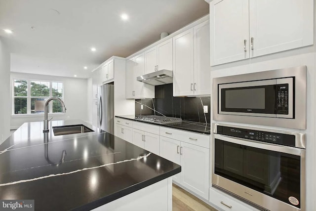 kitchen with backsplash, sink, white cabinets, and stainless steel appliances