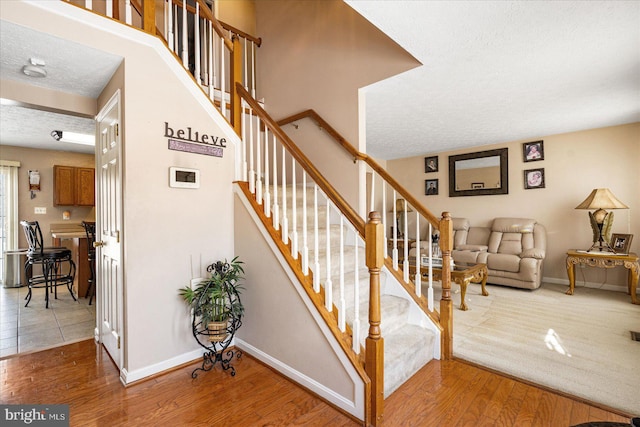 staircase featuring wood-type flooring and a textured ceiling