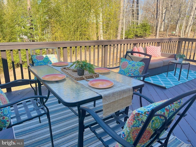 deck with a wooded view and outdoor dining space