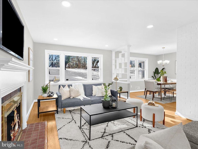 living room with a tile fireplace, light hardwood / wood-style flooring, and a notable chandelier