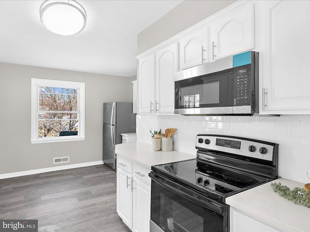 kitchen featuring decorative backsplash, appliances with stainless steel finishes, dark hardwood / wood-style floors, and white cabinetry