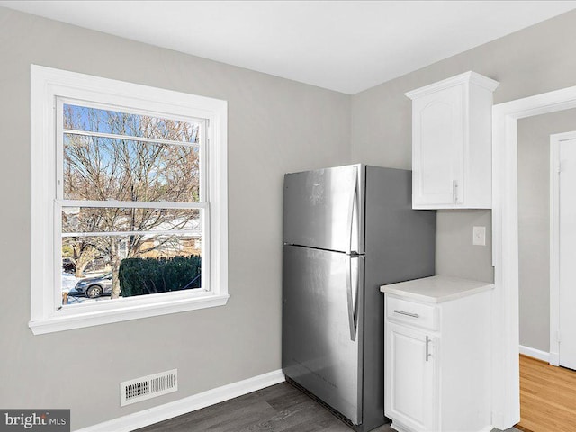 kitchen featuring stainless steel fridge, white cabinets, and dark hardwood / wood-style floors