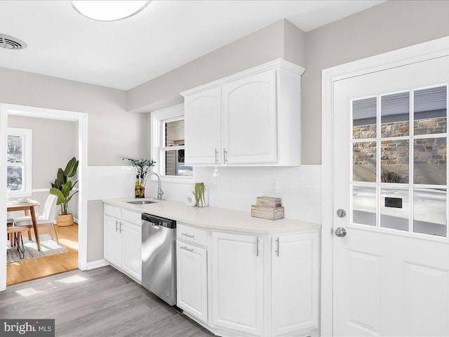 kitchen featuring sink, light hardwood / wood-style flooring, stainless steel dishwasher, a healthy amount of sunlight, and white cabinetry