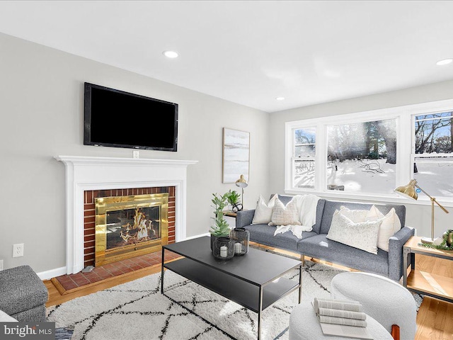 living room with wood-type flooring and a brick fireplace