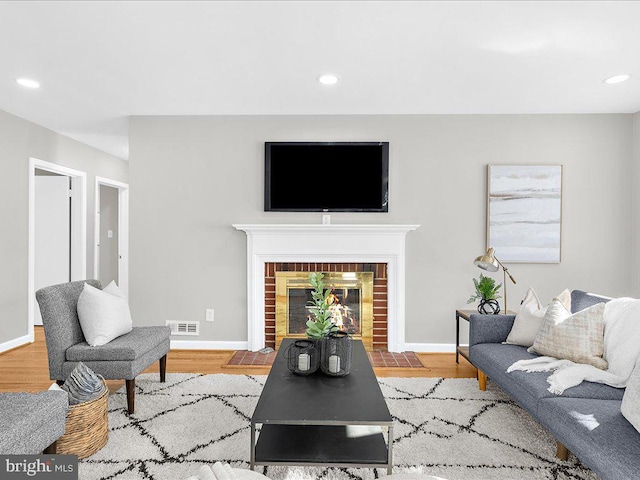 living room with light wood-type flooring and a brick fireplace