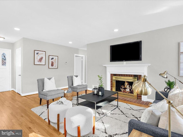 living room with wood-type flooring and a brick fireplace