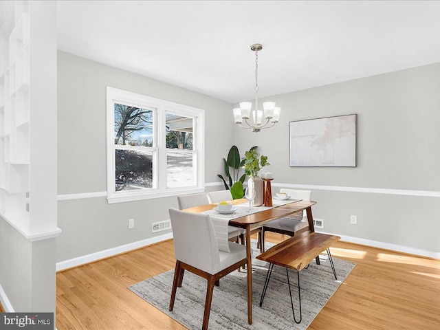 dining space featuring light wood-type flooring and an inviting chandelier