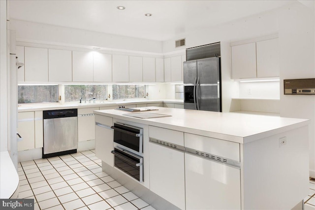 kitchen with sink, white cabinets, light tile patterned flooring, a kitchen island, and appliances with stainless steel finishes