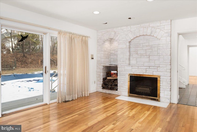 unfurnished living room with a stone fireplace and wood-type flooring