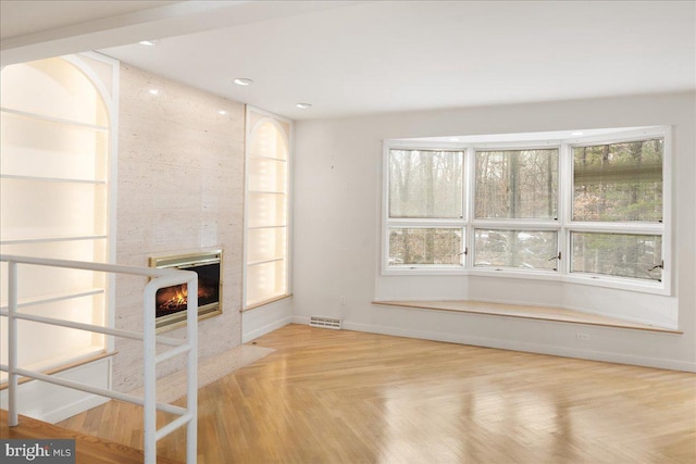 unfurnished living room featuring a large fireplace and light parquet flooring