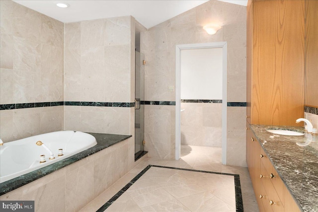 bathroom with tile walls, vanity, and shower with separate bathtub