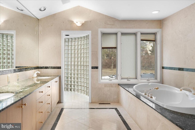 bathroom with a relaxing tiled tub, tile patterned floors, vanity, tile walls, and lofted ceiling