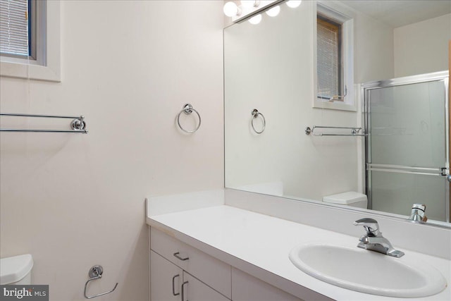 bathroom with vanity, a shower with shower door, and toilet