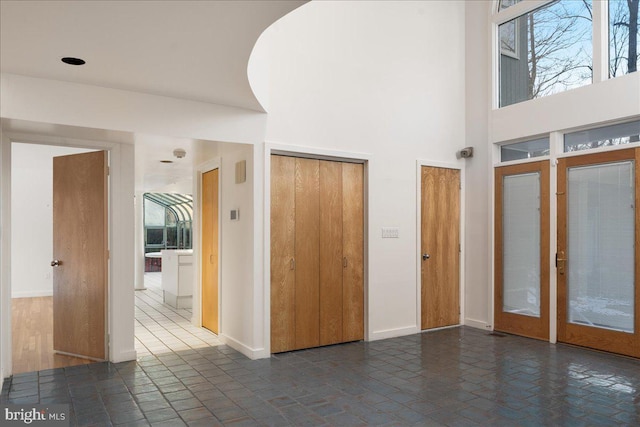 entrance foyer featuring a high ceiling, french doors, and dark tile patterned flooring