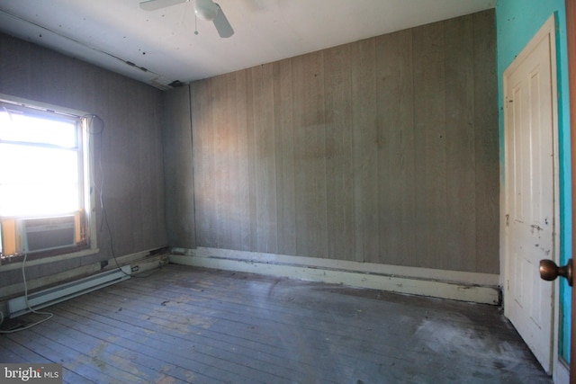 empty room with cooling unit, wooden walls, ceiling fan, and wood-type flooring