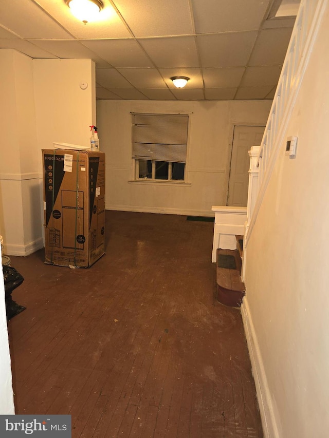 basement with a drop ceiling and dark hardwood / wood-style flooring