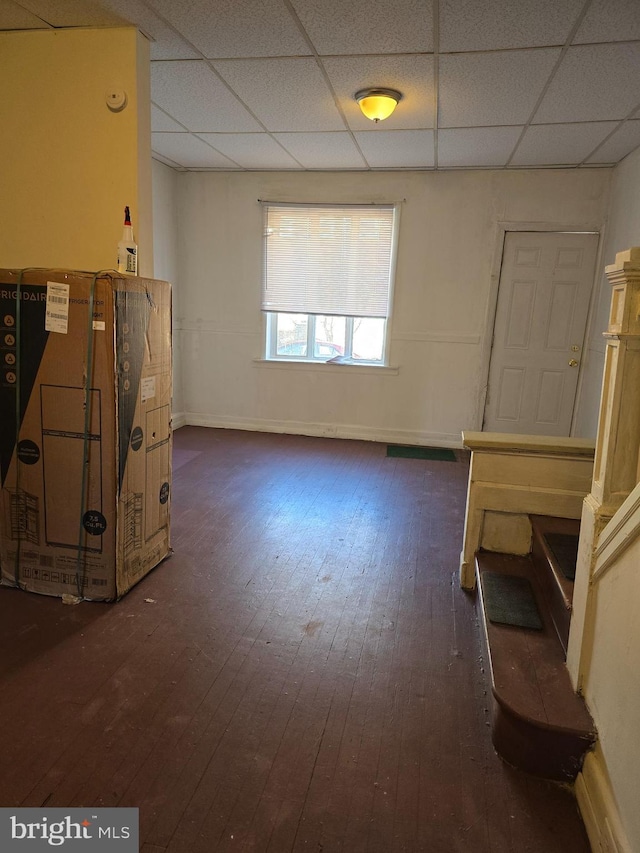 empty room featuring a paneled ceiling and dark hardwood / wood-style flooring