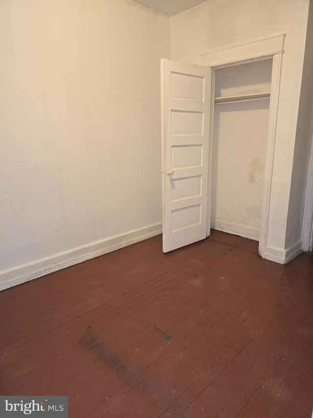 unfurnished bedroom featuring a closet and dark hardwood / wood-style flooring