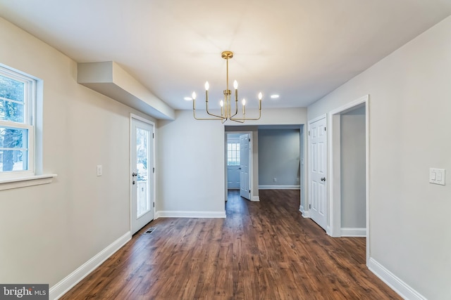 unfurnished dining area featuring dark hardwood / wood-style floors and a chandelier