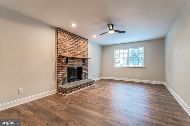 unfurnished living room with ceiling fan, dark hardwood / wood-style flooring, and a brick fireplace