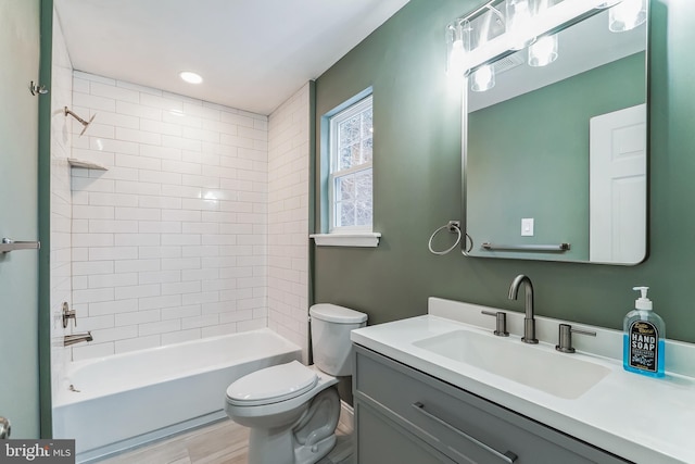 full bathroom with toilet, tiled shower / bath, and vanity