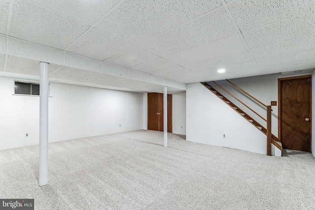 basement with a drop ceiling and carpet