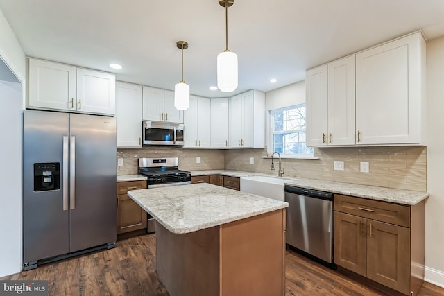 kitchen with hanging light fixtures, a kitchen island, stainless steel appliances, and white cabinetry