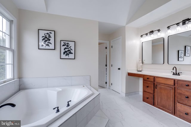 bathroom with plenty of natural light, a garden tub, marble finish floor, and vanity