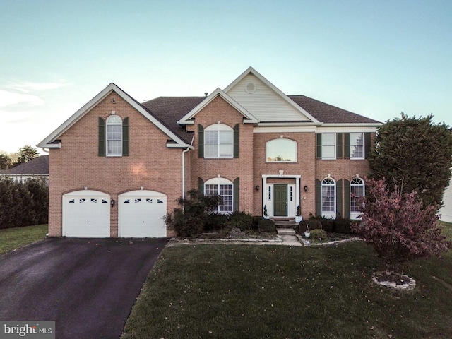 view of front of home with brick siding, driveway, an attached garage, and a front yard