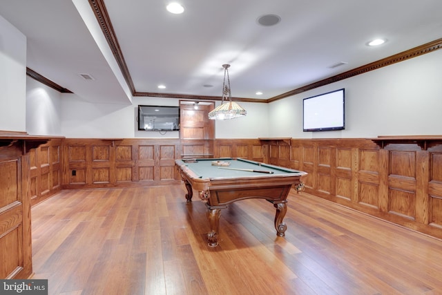 rec room with a wainscoted wall, visible vents, light wood-style floors, and ornamental molding