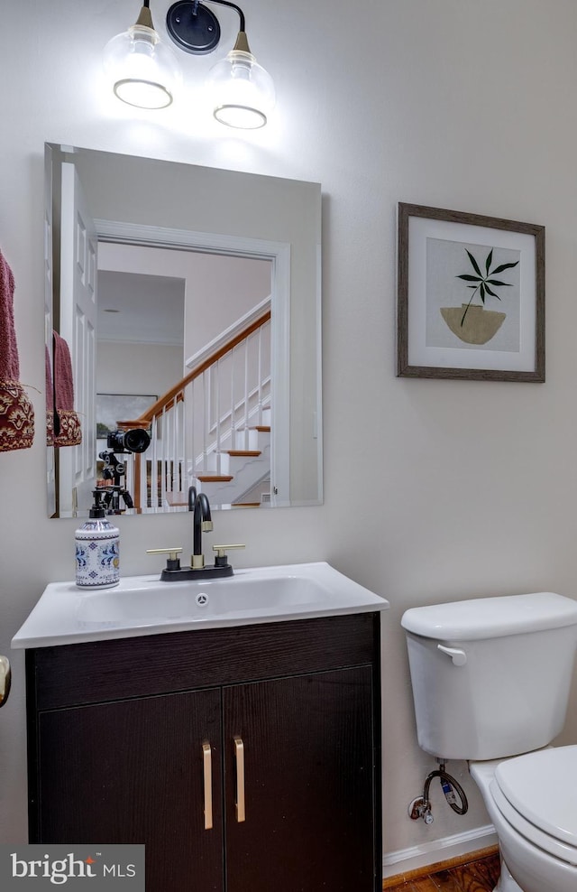 bathroom with toilet, vanity, and baseboards