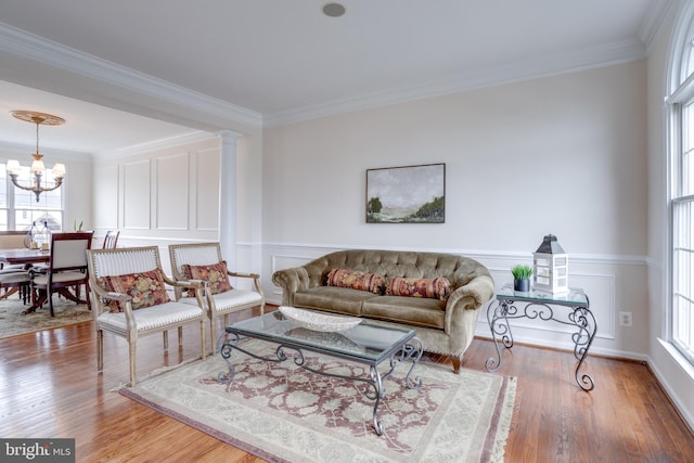 living room with a decorative wall, crown molding, an inviting chandelier, and wood finished floors