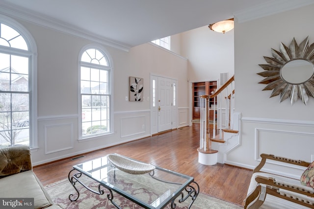 entryway featuring visible vents, crown molding, stairs, and wood finished floors