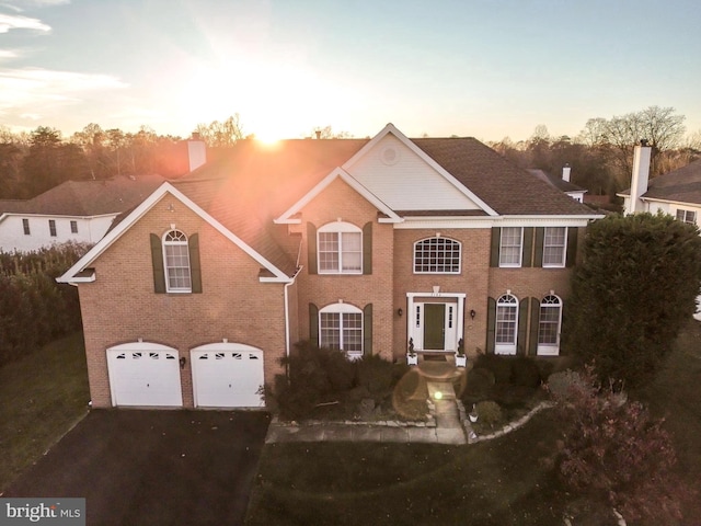 view of front of home featuring aphalt driveway, brick siding, and an attached garage