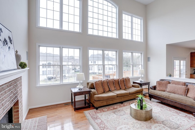 living area with a healthy amount of sunlight, a fireplace, baseboards, and wood finished floors