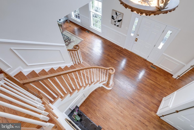 foyer entrance with visible vents, wood finished floors, wainscoting, and a decorative wall