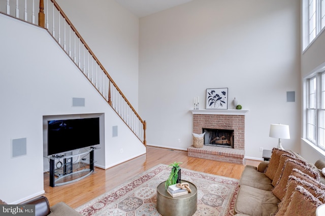 living room featuring a wealth of natural light, stairway, wood finished floors, and a towering ceiling