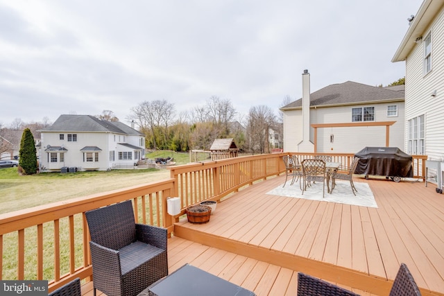 wooden deck with outdoor dining space, a yard, and grilling area