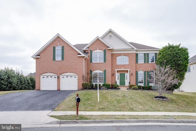 colonial home featuring brick siding, a garage, a front lawn, and driveway