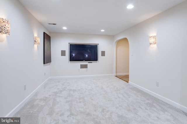 unfurnished living room with visible vents, baseboards, carpet floors, recessed lighting, and arched walkways