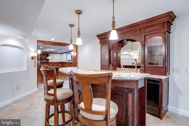 bar with indoor wet bar, hanging light fixtures, wainscoting, and wooden walls