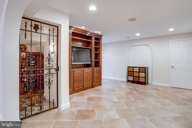 unfurnished living room with recessed lighting, arched walkways, and baseboards