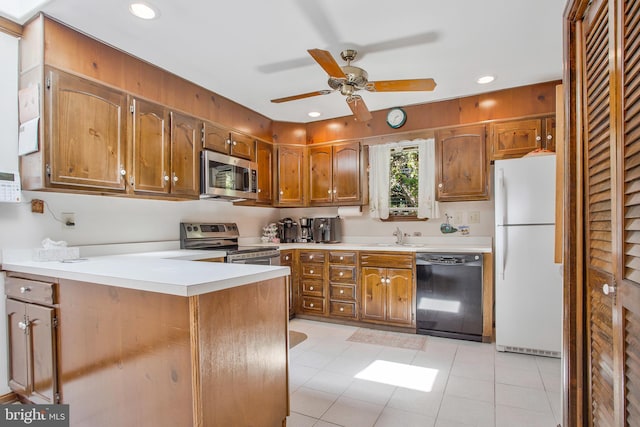 kitchen with kitchen peninsula, appliances with stainless steel finishes, ceiling fan, sink, and light tile patterned flooring