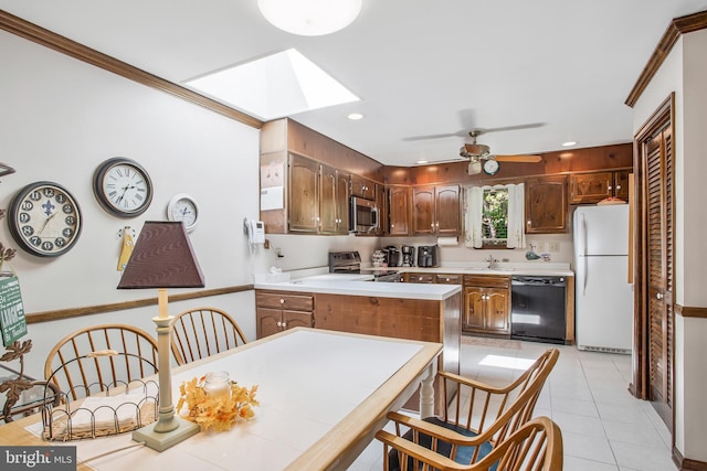 kitchen with a skylight, ceiling fan, kitchen peninsula, light tile patterned flooring, and appliances with stainless steel finishes