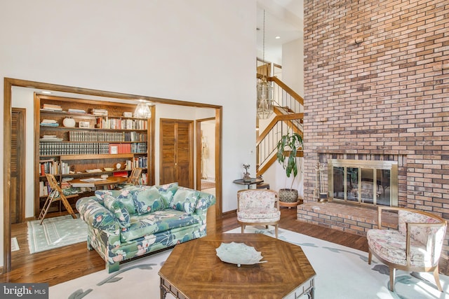 living room featuring wood-type flooring, a fireplace, and a towering ceiling