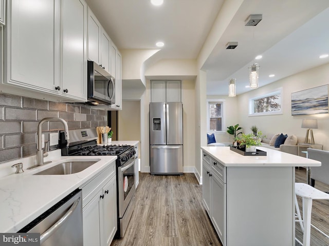 kitchen with white cabinets, appliances with stainless steel finishes, tasteful backsplash, sink, and a breakfast bar area