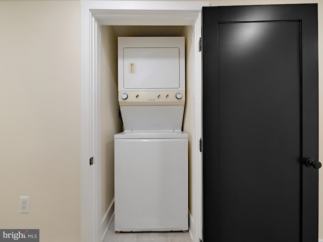 clothes washing area featuring stacked washer and dryer and light tile patterned flooring