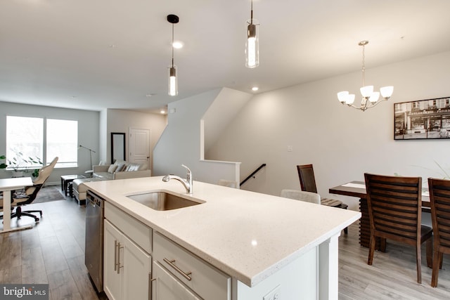 kitchen featuring an island with sink, hanging light fixtures, stainless steel dishwasher, white cabinets, and sink