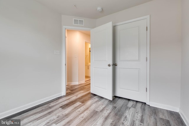 unfurnished bedroom with a closet and light hardwood / wood-style floors