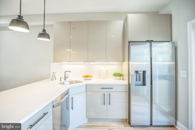 kitchen with gray cabinetry, sink, tasteful backsplash, decorative light fixtures, and stainless steel appliances